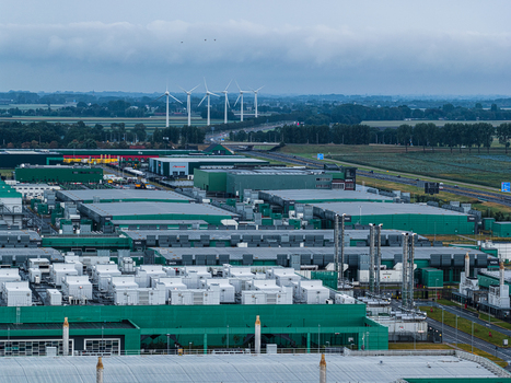 Aerial view of Agriport A7 a large scale greenhouse and data center hub with industrial buildings cooling units and wind turbines in the background Middenmeer Noord Holland Netherlands. Aerial view of Agriport A7 a large scale greenhouse and data center hub with industrial buildings cooling units and wind turbines in the background Middenmeer Noord Holland Netherlands.