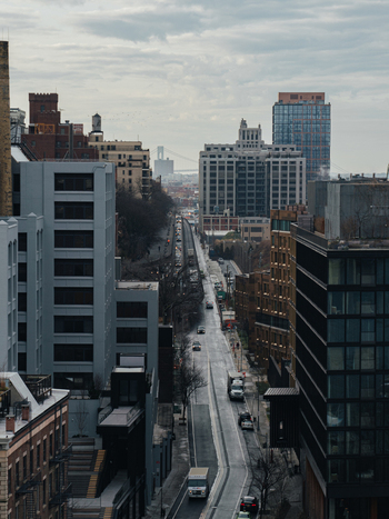 View of a street in Brooklyn with modern and historic buildings cars on the road and a bridge in the distance in New York New York United States.