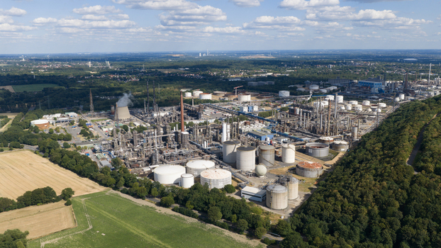 Aerial view of the Tanklager industrial facility with large storage tanks processing towers and cooling structures near forests and fields in Gelsenkirchen North Rhine Westphalia Germany.