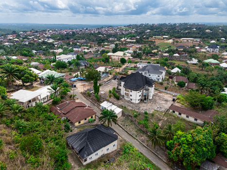 Aerial view of rooftops trees and roads create a textured mosaic under a cloudy sky revealing the serene beauty of the residential area Asaga Abia Nigeria. Aerial view of rooftops trees and roads create a textured mosaic under a cloudy sky revealing the serene beauty of the residential area Asaga Abia Nigeria.