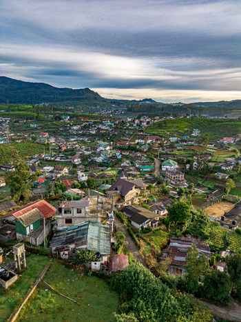 Aerial view of Nuwara Eliya nestled among lush green tea plantations and rolling hills under a dramatic cloudy sky in Nuwara Eliya Central Province Sri Lanka. Aerial view of Nuwara Eliya nestled among lush green tea plantations and rolling hills under a dramatic cloudy sky in Nuwara Eliya Central Province Sri Lanka.