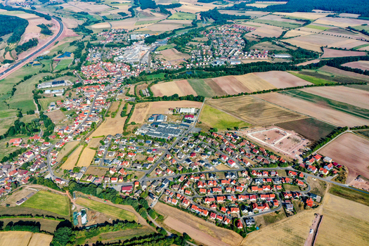 Aerial view of the town of Schlusselfeld featuring red roofed houses industrial buildings and surrounding green and golden agricultural fields Schlusselfeld Bavaria Germany. Aerial view of the town of Schlusselfeld featuring red roofed houses industrial buildings and surrounding green and golden agricultural fields Schlusselfeld Bavaria Germany.
