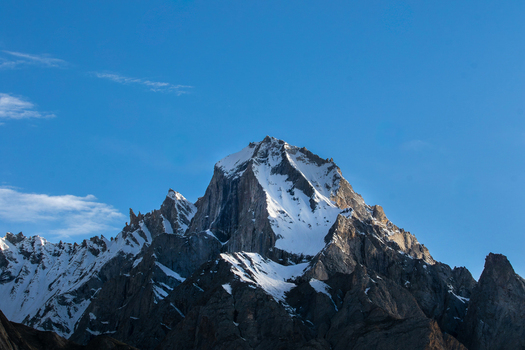 View of K2 peak with snow covered slopes and rocky ridges under a clear blue sky in Gilgit Pakistan. View of K2 peak with snow covered slopes and rocky ridges under a clear blue sky in Gilgit Pakistan.