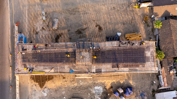 Aerial view of construction workers installing steel rebar framework for a building foundation at a construction site in Indonesia. Aerial view of construction workers installing steel rebar framework for a building foundation at a construction site in Indonesia.