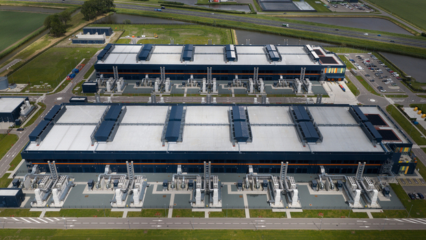 Aerial view of the Agriport data center complex featuring large industrial buildings with cooling systems and surrounding green fields in Middenmeer Noord Holland Netherlands. Aerial view of the Agriport data center complex featuring large industrial buildings with cooling systems and surrounding green fields in Middenmeer Noord Holland Netherlands.