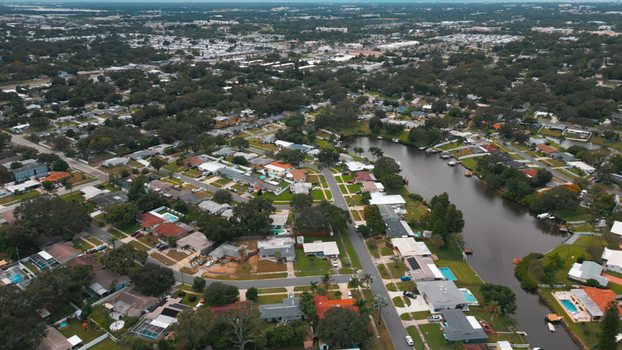 Aerial view of a residential neighborhood with houses swimming pools and a winding canal surrounded by lush trees in Clearwater Florida United States.
