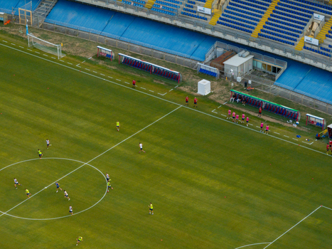 Aerial view of Stadio Riviera delle Palme with football players training on the green pitch surrounded by blue stadium seating in San Benedetto del Tronto Marche Italy.
