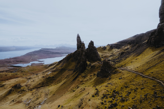 Aerial view of The Storr a dramatic basalt rock formation on the Isle of Skye featuring rugged grassy slopes and winding hiking trails in Portree Scotland United Kingdom. Aerial view of The Storr a dramatic basalt rock formation on the Isle of Skye featuring rugged grassy slopes and winding hiking trails in Portree Scotland United Kingdom.