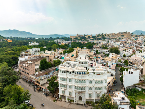 Aerial view of a white haveli style building with traditional arches surrounded by the urban landscape and historic architecture of Udaipur Rajasthan India. Aerial view of a white haveli style building with traditional arches surrounded by the urban landscape and historic architecture of Udaipur Rajasthan India.