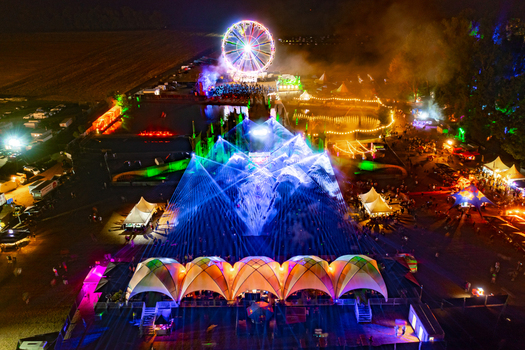 Herzogenaurach Germany 22 July 2022 Aerial view of Open Beatz Festival with a vibrant laser light show illuminated Ferris wheel and crowds of people at night. Herzogenaurach Germany 22 July 2022 Aerial view of Open Beatz Festival with a vibrant laser light show illuminated Ferris wheel and crowds of people at night.