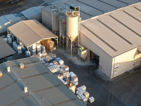 Kilsyth VIC Australia 22 September 2026 Aerial view of industrial factories featuring large storage silos corrugated metal roofs and stacked shipping containers in the yard. Kilsyth VIC Australia 22 September 2026 Aerial view of industrial factories featuring large storage silos corrugated metal roofs and stacked shipping containers in the yard.