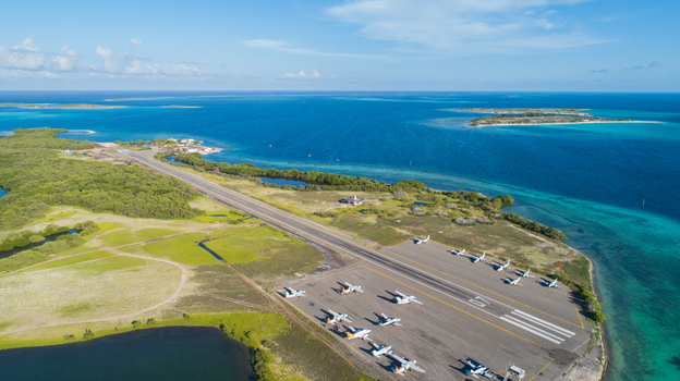 Aerial view of Los Roques airport runway with small aircraft on the tarmac surrounded by turquoise Caribbean waters in Los Roques Dependencias Federale Venezuela. Aerial view of Los Roques airport runway with small aircraft on the tarmac surrounded by turquoise Caribbean waters in Los Roques Dependencias Federale Venezuela.