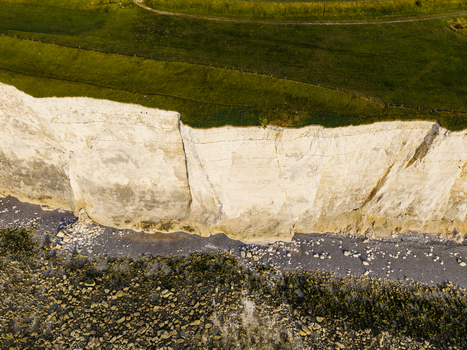Aerial view of the Beach of the Bois de Cise featuring white chalk cliffs green grassy clifftops and a rocky shoreline in Ault Hauts de France France.
