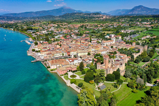 Aerial view of the historic Scaligero Castle and colorful lakeside buildings along the turquoise waters of Lake Garda in Provincia di Verona Veneto Italy.