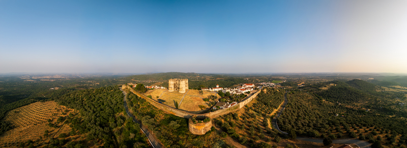 Aerial view of Castle of Evoramonte surrounded by historic stone walls olive groves and rolling hills under a clear blue sky in Evora Monte Distrito de Evora Portugal.