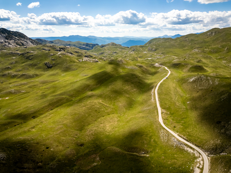 Aerial view of Bobotov Kuk and the winding road through the green mountainous landscape of Zabljak Municipality Montenegro. Aerial view of Bobotov Kuk and the winding road through the green mountainous landscape of Zabljak Municipality Montenegro.