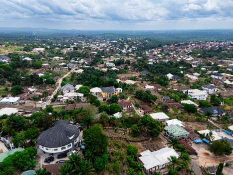 Aerial view of a residential landscape with varied rooftops peeking through abundant green trees under an overcast sky Asaga Abia Nigeria. Aerial view of a residential landscape with varied rooftops peeking through abundant green trees under an overcast sky Asaga Abia Nigeria.