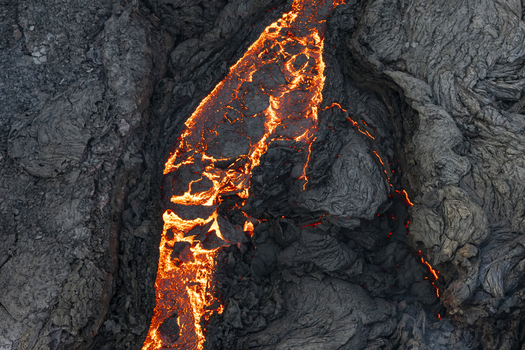 Aerial view of molten rock and magma snake through the cooled jagged terrain of the Sundhn&uacute;kur Eruption Reykjavik Reykjanes Iceland.