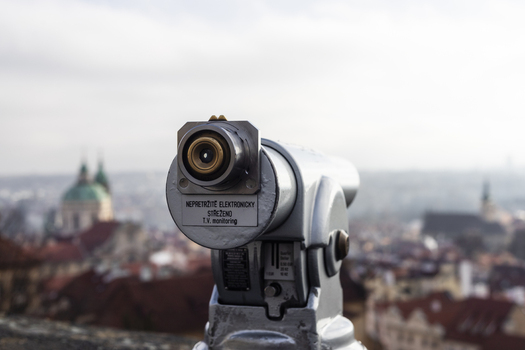 View of a tourist telescope overlooking the historic red rooftops and the green dome of St. Nicholas Church in Prague Prague Czechia. View of a tourist telescope overlooking the historic red rooftops and the green dome of St. Nicholas Church in Prague Prague Czechia.