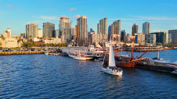 Aerial view of the San Diego skyline and waterfront featuring the North Embarcadero historic tall ships and modern sailboats docked in the harbor San Diego California United States.