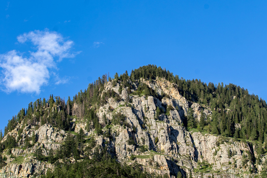 View of rugged rocky mountain peaks and dense pine forests under a clear blue sky in Kumrat Valley Khyber Pakhtunkhwa Pakistan. View of rugged rocky mountain peaks and dense pine forests under a clear blue sky in Kumrat Valley Khyber Pakhtunkhwa Pakistan.