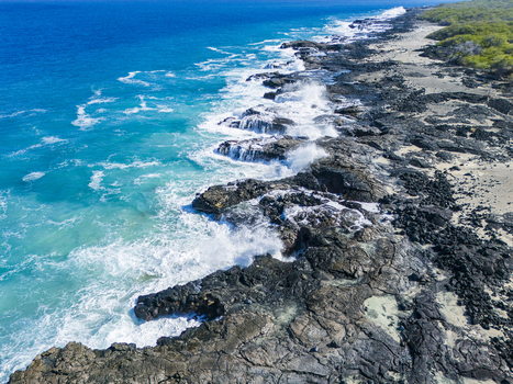 Aerial view of Kalaemamo coastline with turquoise ocean waves crashing against black volcanic rocks and lush green vegetation Hawaii County Hawaii United States. Aerial view of Kalaemamo coastline with turquoise ocean waves crashing against black volcanic rocks and lush green vegetation Hawaii County Hawaii United States.