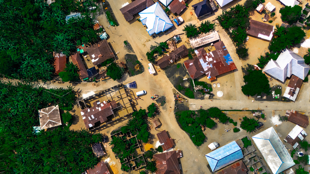 Aerial view of residential houses with metal roofs dirt roads and lush green vegetation in the village of Abua Rivers Nigeria. Aerial view of residential houses with metal roofs dirt roads and lush green vegetation in the village of Abua Rivers Nigeria.