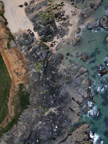 Aerial view of the rugged rocky coastline and sandy shores of Godrevy Beach with turquoise sea water and waves crashing against the cliffs in Gwithian England United Kingdom. Aerial view of the rugged rocky coastline and sandy shores of Godrevy Beach with turquoise sea water and waves crashing against the cliffs in Gwithian England United Kingdom.