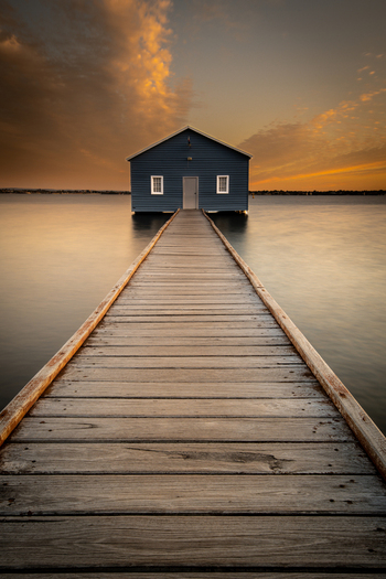 View of the iconic Blue Boat House at the end of a long wooden jetty over the Swan River during a golden sunset in Crawley Western Australia Australia. View of the iconic Blue Boat House at the end of a long wooden jetty over the Swan River during a golden sunset in Crawley Western Australia Australia.