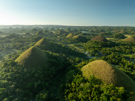 Aerial view of the Chocolate Hills a geological formation of grass covered limestone mounds under a clear sky in Batuan Central Visayas Philippines. Aerial view of the Chocolate Hills a geological formation of grass covered limestone mounds under a clear sky in Batuan Central Visayas Philippines.