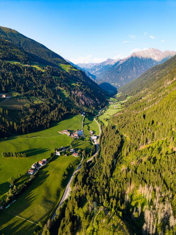 Aerial view of the valley of Muhlwald with lush green meadows dense pine forests and a winding road leading through the village in Muhlwald Trentino Alto Adige Italy. Aerial view of the valley of Muhlwald with lush green meadows dense pine forests and a winding road leading through the village in Muhlwald Trentino Alto Adige Italy.