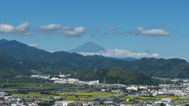 Aerial view of Mount Fuji rising above the green mountains and urban landscape of Shizuoka Shizuoka Japan.