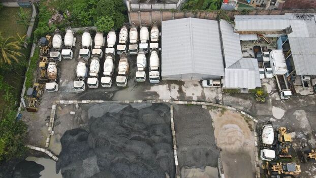 Serpong Sub District Banten Indonesia 11 May 2022 Aerial view of a concrete batching plant with numerous cement mixer trucks parked in rows next to piles of gravel and sand. Serpong Sub District Banten Indonesia 11 May 2022 Aerial view of a concrete batching plant with numerous cement mixer trucks parked in rows next to piles of gravel and sand.