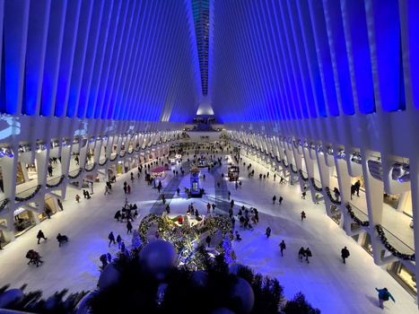 View of the interior of The Oculus at the World Trade Center with its white ribbed architecture blue lighting and people walking among holiday decorations New York New York United States. View of the interior of The Oculus at the World Trade Center with its white ribbed architecture blue lighting and people walking among holiday decorations New York New York United States.