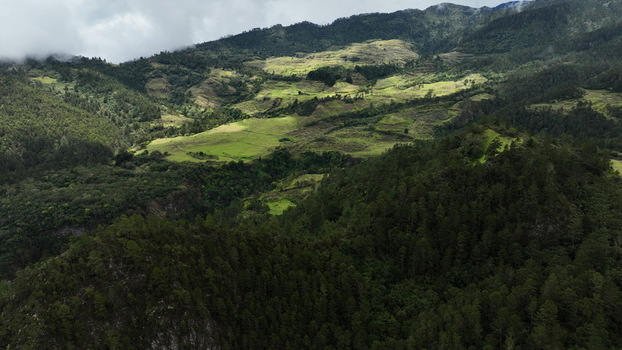Aerial view of the mountainous landscape near the Carretera al Salto de Aguas Blancas featuring pine forests rolling hills and agricultural fields in Constanza La Vega Dominican Republic.