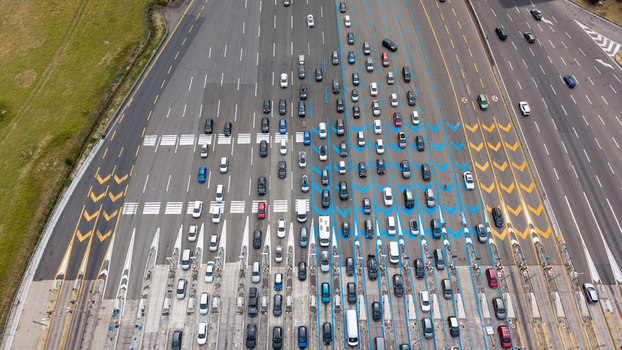 Aerial view of the Autostrada A1 Melegnano toll plaza featuring organized vehicle access lanes highway infrastructure and road markings in Melegnano Lombardy Italy.