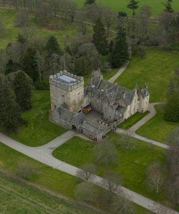 Aerial view of Drum Castle Garden and Estate featuring its historic stone tower and manor house surrounded by lush green lawns and woodland in Drumoak Scotland United Kingdom.