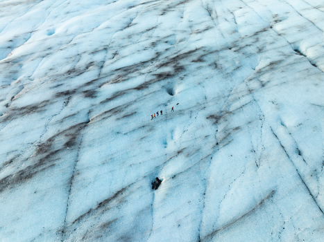 Aerial view of Breidamerkurjokull glacier with a group of hikers walking across the blue ice and dark volcanic ash streaks in Sveitarfelagid Hornafjordur Iceland. Aerial view of Breidamerkurjokull glacier with a group of hikers walking across the blue ice and dark volcanic ash streaks in Sveitarfelagid Hornafjordur Iceland.