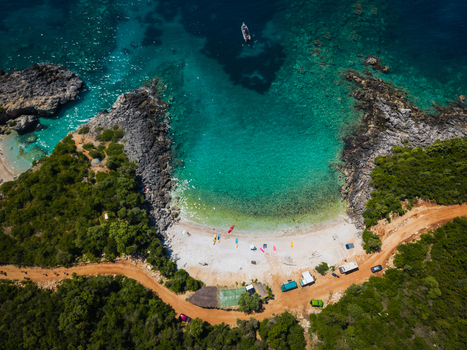 Aerial view of Aquarium Beach featuring turquoise waters white pebbles and lush green vegetation in Jala Vlore County Albania. Aerial view of Aquarium Beach featuring turquoise waters white pebbles and lush green vegetation in Jala Vlore County Albania.