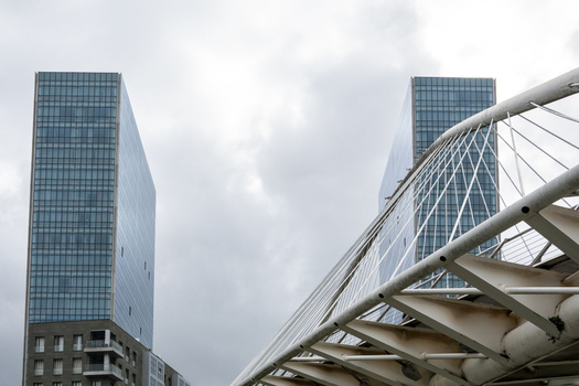 View of the modern Isozaki Atea twin towers and the white steel cables of the Zubizuri bridge under a cloudy sky in Greater Bilbao Basque Country Spain. View of the modern Isozaki Atea twin towers and the white steel cables of the Zubizuri bridge under a cloudy sky in Greater Bilbao Basque Country Spain.