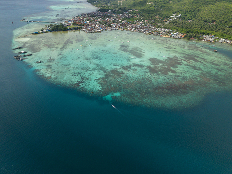 Aerial view of turquoise waters meet the shore revealing a vibrant reef system contrasting with the deep blue ocean Karimunjawa Central Java Indonesia. Aerial view of turquoise waters meet the shore revealing a vibrant reef system contrasting with the deep blue ocean Karimunjawa Central Java Indonesia.