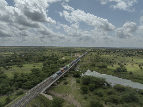 Aerial view of a freight train with colorful shipping containers crossing a railway bridge over a river in the Swara Plains Conservancy Nairobi Machakos County Kenya. Aerial view of a freight train with colorful shipping containers crossing a railway bridge over a river in the Swara Plains Conservancy Nairobi Machakos County Kenya.
