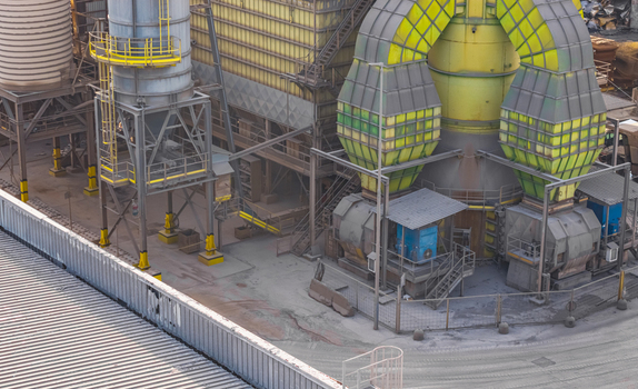 Aerial view of an industrial air filtration and dust extraction system with large metal ducts processing equipment and heavy manufacturing infrastructure in Italy.