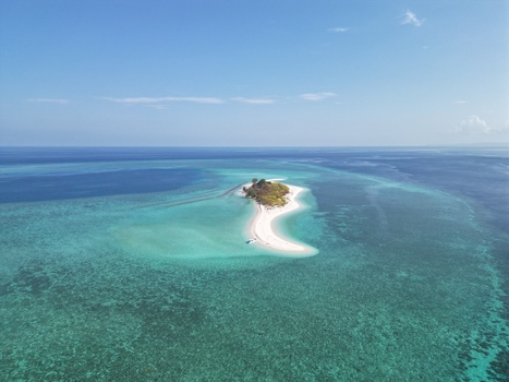 Aerial view of Pulau Ndaa a small tropical island with a white sand beach surrounded by turquoise coral reefs and clear blue water in Tomia South East Sulawesi Indonesia.