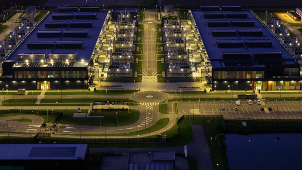Aerial view of the Microsoft Data Center at night featuring illuminated industrial buildings parking lots and a central access road in Middenmeer North Holland Netherlands.