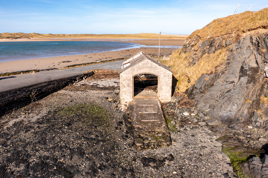 Aerial view of the historic stone boat house at Ballyness Bay situated on the sandy coastline with rocky cliffs and clear blue sky in Ballyness County Donegal Ireland. Aerial view of the historic stone boat house at Ballyness Bay situated on the sandy coastline with rocky cliffs and clear blue sky in Ballyness County Donegal Ireland.