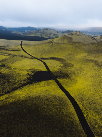 Aerial view of a stark road cutting through the vibrant green and dark moss covered landscape under a brooding sky Lakagigar Iceland. Aerial view of a stark road cutting through the vibrant green and dark moss covered landscape under a brooding sky Lakagigar Iceland.
