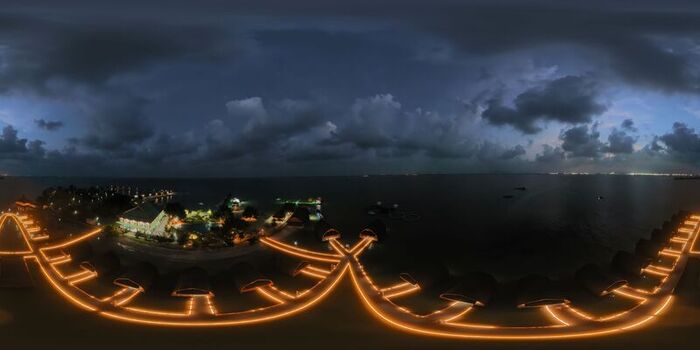 Aerial view of Pulau Lima Resort at night with illuminated walkways connecting overwater bungalows above the dark ocean under a cloudy sky in Kasemen Banten Indonesia. Aerial view of Pulau Lima Resort at night with illuminated walkways connecting overwater bungalows above the dark ocean under a cloudy sky in Kasemen Banten Indonesia.