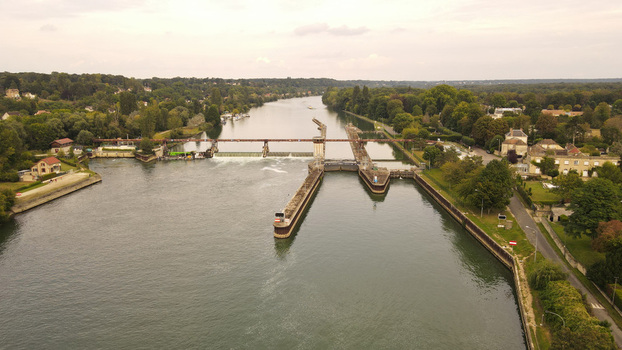 Aerial view of the river lock and dam on the Seine River surrounded by lush trees and residential houses in Chartrettes Ile de France France. Aerial view of the river lock and dam on the Seine River surrounded by lush trees and residential houses in Chartrettes Ile de France France.