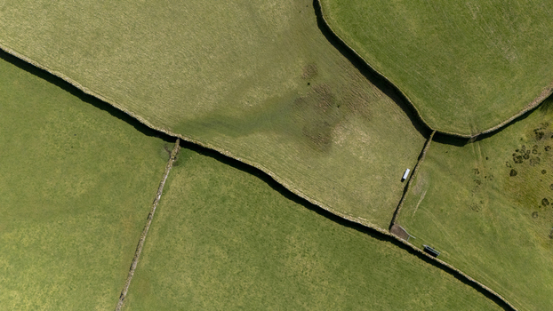 Aerial view of vibrant green fields divided by stone walls creating a patchwork of textures and tones under the soft sunlight England United Kingdom. Aerial view of vibrant green fields divided by stone walls creating a patchwork of textures and tones under the soft sunlight England United Kingdom.